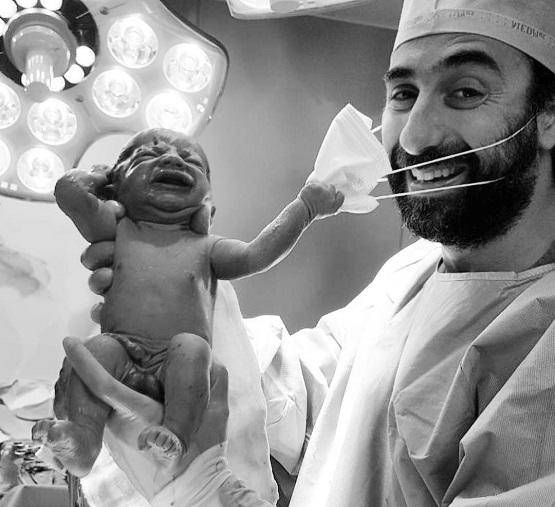 طفل حديث الولادة ينزع الكمامة عن وجه الطبيب