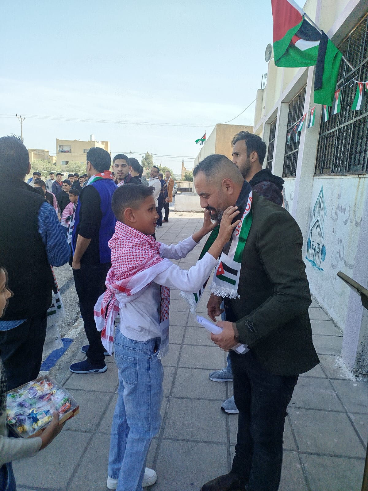 بمناسبة يوم العلم.. الطالب عبد الله حمزه  الدحادحه  يوزع العلم الاردني  في مدرسة حور الثانوية الشاملة للبنين